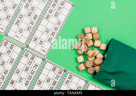 Lotto in legno Barili con borsa di stoffa e carte da gioco su sfondo verde. Gioco di bordo del lotto. Vista dall'alto. Foto Stock