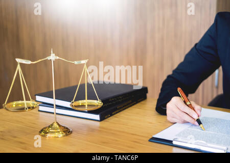 Avvocato giudice alla lettura di documenti al banco in aula lavorando sulla scrivania in legno sfondo. martello Peso d'oro. e soundblock di giustizia Foto Stock