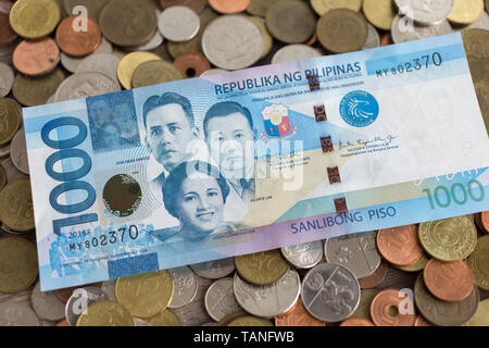 Un mucchio di nuovi e vecchi Philippine peso le monete con un migliaio di banconota su di esso Foto Stock