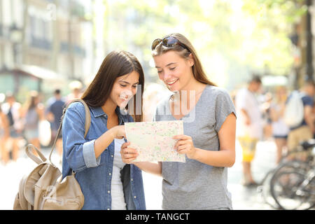 Felici turisti controllo guida della carta in posizione di ricerca in piedi in strada Foto Stock