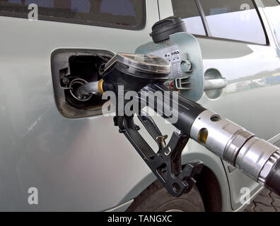 Auto in una stazione di benzina. La benzina la pompa a pistola inserito in un serbatoio Foto Stock