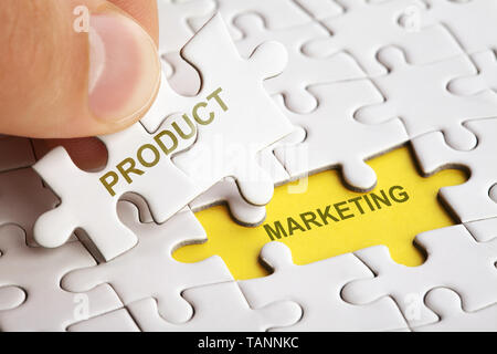 Mano azienda pezzo del puzzle con word il marketing del prodotto. Foto Stock