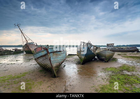 Abbandonate le barche da pesca sotto un cielo meditabondo sul Pin mulino sul fiume Orwell Near Ipswich sulla costa di Suffolk Foto Stock