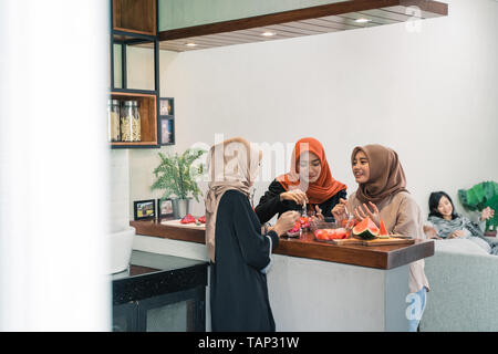 Tre donne velate chiacchierando in cucina in attesa interrompendo il loro veloce Foto Stock