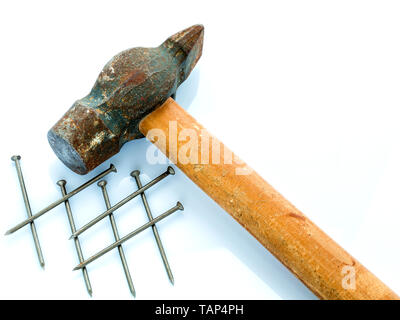 Un vecchio martello con un manico di legno e un mucchio di chiodi. Gli oggetti su uno sfondo luminoso Foto Stock
