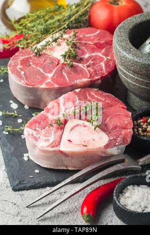 Freschi Stinco di vitello fette di carne di manzo per osso buco per la cottura sul tagliere con ingredienti e condimenti timo, pepe, sale. Foto Stock