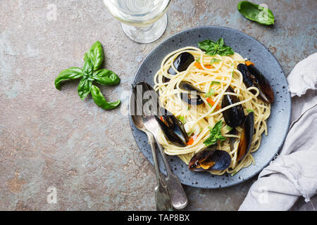 Spaghetti allo scoglio, Pasta con pesce e frutti di mare, cozze in grigio di una piastra di ceramica su sfondo di pietra, vista dall'alto Foto Stock