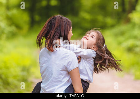 Giovane mamma trattiene e gira la sua bambina nella foresta.Felice madre e figlia momenti con amore e commozione naturale.Foto della giovane madre e il suo daug Foto Stock