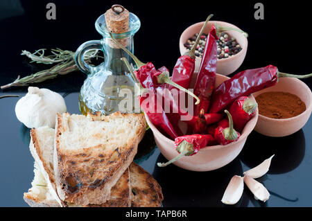 Peperoncino rosso, olio, pane, aglio e pepe in un vaso di argilla; Foto Stock