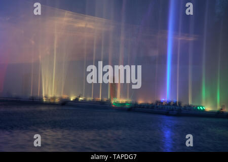 Acqua colorata fontane con il laser e la riflessione della luce sul lago. Foto Stock