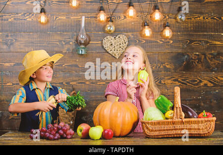 Mercato di fattoria. Bambini presentando farm raccolto lo sfondo di legno. Gli agricoltori per bambini ragazza ragazzo verdure raccolto. Agricoltura insegna ai bambini dove il loro cibo proviene da. I fratelli avendo divertimento. Azienda agricola a conduzione familiare. Foto Stock