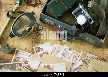 Retrò maschera e pinne con una valigia, notebook, mappa vecchia, Le cartoline ricordo e attrezzature di viaggio / Concetto di vacanza Foto Stock