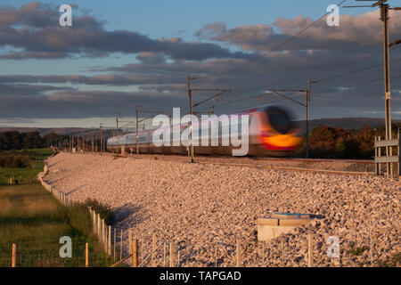 Virgin Trains west coast treno pendolino accelerando lungo la linea principale della costa occidentale Foto Stock