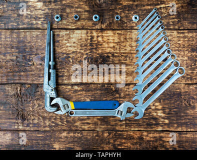 Set di chiavi a combinazione e vecchie chiavi regolabili su un vecchio di tavole di legno sfondo con un posto per uno spazio di copia Foto Stock