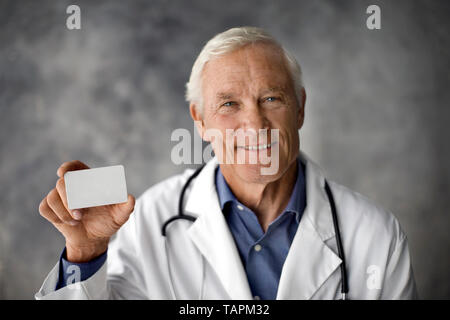 Medico sorridente con in mano una carta bianca. Foto Stock