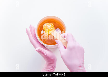 Concetto di zuccheraggio. flat laici. vista aerea del recipiente con la cosmetologia miele. bastone di legno Foto Stock