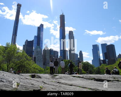 New York, Stati Uniti d'America. 15 Maggio, 2019. Persone in Central Park sono in cerca di enormi grattacieli. Nuovi grattacieli stanno sorgendo in New York. Alcuni utilizzano scappatoie per offrire ai loro clienti facoltosi una vista fantastica. Ma non vi è resistenza. (A dpa 'million attici in 400 metri di altezza: chi possiede di New York skyline?' dal 27.05.2019) Credito: Benno Schwinghammer/dpa/Alamy Live News Foto Stock