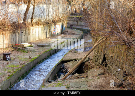 Il fiume sporco Lybid fluisce lungo un vecchio, danneggiati, usurati canale racchiuso in uno scivolo di cemento. Un disastro ecologico della città moderna. Foto Stock