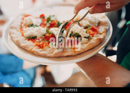 Il cameriere serve pizza su un piatto di portata Foto Stock