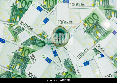 Rotolo di banconote in euro, molte banconote di 100 Euro, la moneta europea sullo sfondo Foto Stock