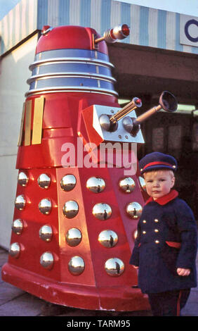 Archival toddler boy negli anni sessanta domenica miglior abbigliamento pone accanto alla replica del famoso Dalek mutante dal BBC science fiction programma televisivo London REGNO UNITO Foto Stock