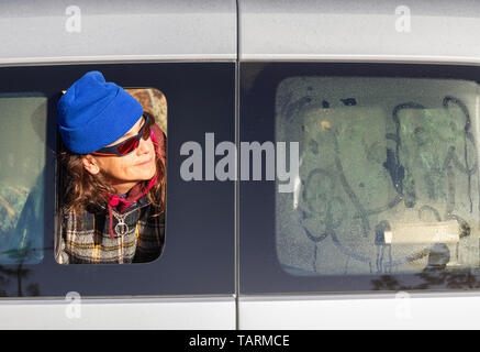 Donna che guarda fuori del camper finestra a sunrise. Foto Stock