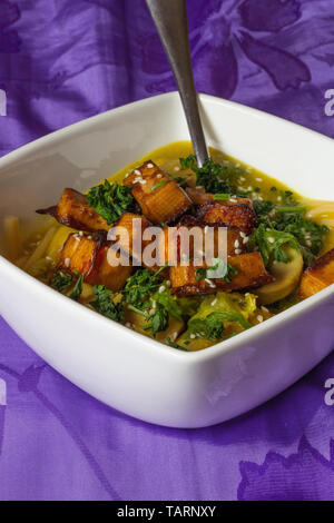 Stufati di funghi con tofu affumicato in vaschetta bianca spruzzata con sesamo sfondo scuro vista verticale Foto Stock