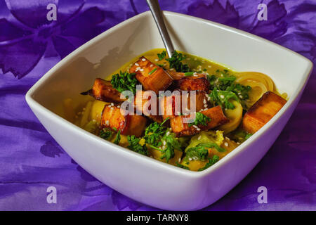 Stufati di funghi con tofu affumicato in vaschetta bianca spruzzata con sesamo sfondo scuro Foto Stock