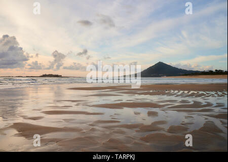 Spiaggia di moledo alla fine della giornata, con vista montagna trega sul lato spagnolo del confine. La bassa marea visualizzando la spiaggia sabbiosa su una torbida da Foto Stock