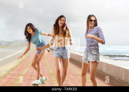 Tre amici ragazza camminare e fare pattinaggio su un sentiero Foto Stock