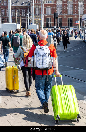 Turisti e visitatori con carrelli, in modo da e per la stazione ferroviaria di Amsterdam Centraal, Paesi Bassi, Foto Stock