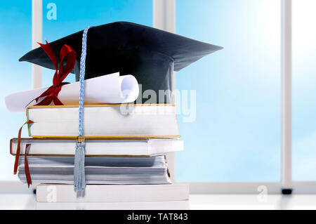 Graduazione hat e diploma sulla pila di libri sul tavolo. Concetto di graduazione Foto Stock