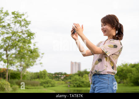 Giovane bella asiatica donna turistica rilassante presso il parco Foto Stock