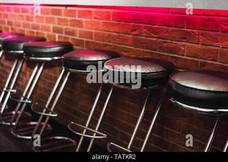 Sgabelli Da Bar presso il contatore in una luce al neon. Le sedie in pelle al bar Foto Stock