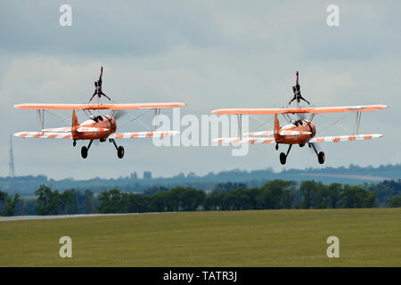 Il AeroSuperBatics Wingwalker team prende il largo per una dimostrazione dell'antenna durante il Duxford Air Festival presso l'Imperial War Museum Duxford, Inghilterra, 26 maggio 2019. Il Wingwalkers eseguire acrobazie e le verticali mentre legato alle ali superiori di 1940's Boeing Stearman biplani. (U.S. Air Force foto di Master Sgt. Eric Burks) Foto Stock