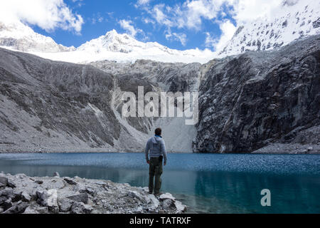 Retro di un giovane backpacker in piedi di fronte del ghiacciaio turchese lago nel Parco Nazionale del Huascaran, Laguna 69, Perù Foto Stock