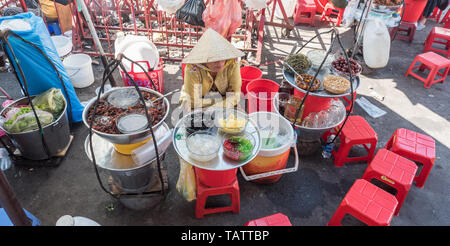 La città di Ho Chi Minh, Vietnam: un venditore si siede da piastre con ingredienti per sam bo luong, un dolce freddo minestra (piatto di origine cinese) Cho Binh Tay mercato. Foto Stock