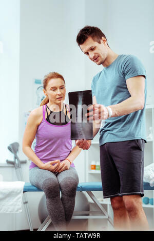 Problema con la spina dorsale. Piacevole bella donna che guarda la X ray immagine mentre si stanno avendo dei problemi con il suo dorso Foto Stock