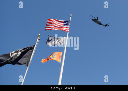 Prato est, New York, Stati Uniti d'America. 25 Maggio, 2019. Un U.S. Navy MH-53E elicottero sorvola pennoni con la bandiera americana, POW-MIA bandiera, e Nassau County bandiera in Veterans Memorial Plaza, come il velivolo si allontana dopo essere stato sul display come parte della flotta per settimana, il sabato del Memorial Day Weekend a Eisenhower Park sull'Isola Lunga. Credito: Ann Parry/ZUMA filo/Alamy Live News Foto Stock