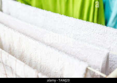Bianche e colorate lenzuola e asciugamani per essere essiccato sul stendibiancheria. Foto Stock