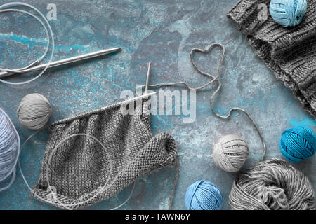 Verde scuro dei filati di lana e aghi di tessitura e maglieria creativa hobby lo sfondo in blu turchese colori Foto Stock