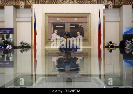 I visitatori a piedi passato un dipinto con Chiang Kai-shek visualizzato in un'area espositiva di documentare Chiang la vita e la carriera al livello inferiore della camera principale del National Chiang Kai-shek Memorial Hall eretto in memoria del Generalissimo Chiang Kai-shek, ex presidente della Repubblica di Cina situato nel quartiere Zhongzheng, Taipei, Taiwan Foto Stock