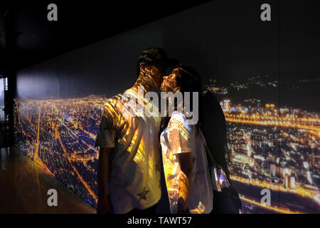 Notte cityscape come visto dal piano superiore di Taipei 101 è proiettato su una coppia giovane kissing presso la hall di Taipei 101 una pietra miliare supertall grattacielo nel quartiere di Xinyi, Taipei, Taiwan. Foto Stock