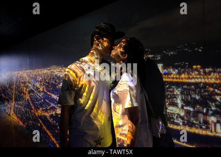 Notte cityscape come visto dal piano superiore di Taipei 101 è proiettato su una coppia giovane kissing presso la hall di Taipei 101 una pietra miliare supertall grattacielo nel quartiere di Xinyi, Taipei, Taiwan. Foto Stock