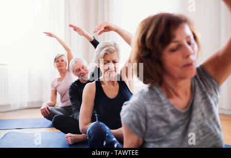 Gruppo di alti di persone facendo esercizi yoga in centro nella comunità club. Foto Stock