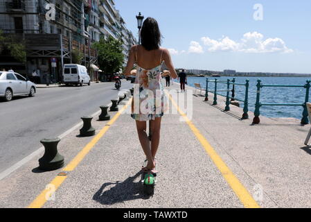 Donna su un elettrico calce scooter a cavallo su un ciclo via lungomare di Salonicco, Grecia. Foto Stock