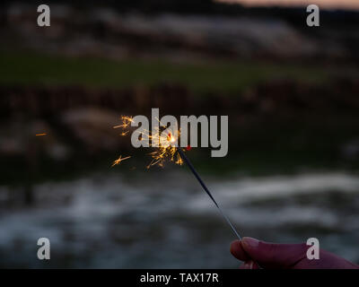 Un irriconoscibile persona con un sparkler sfrigolanti in mano Foto Stock