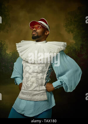 Giovane uomo come un grandee medievale o nobile su studio scuro dello sfondo. Modello maschile in un cappello e occhiali da sole. Ritratto in costume retrò. Le emozioni umane, Foto Stock