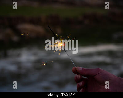 Un irriconoscibile persona con un sparkler sfrigolanti in mano Foto Stock