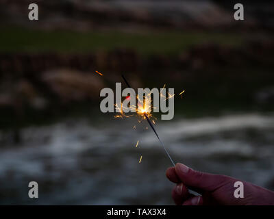 Un irriconoscibile persona con un sparkler sfrigolanti in mano Foto Stock